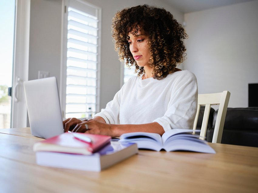 Étudiant avec des livres scolaires ouverts et regardant un ordinateur portable